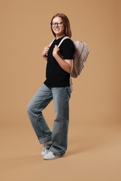 Teenage girl with backpack on beige background