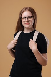 Teenage girl with backpack on beige background