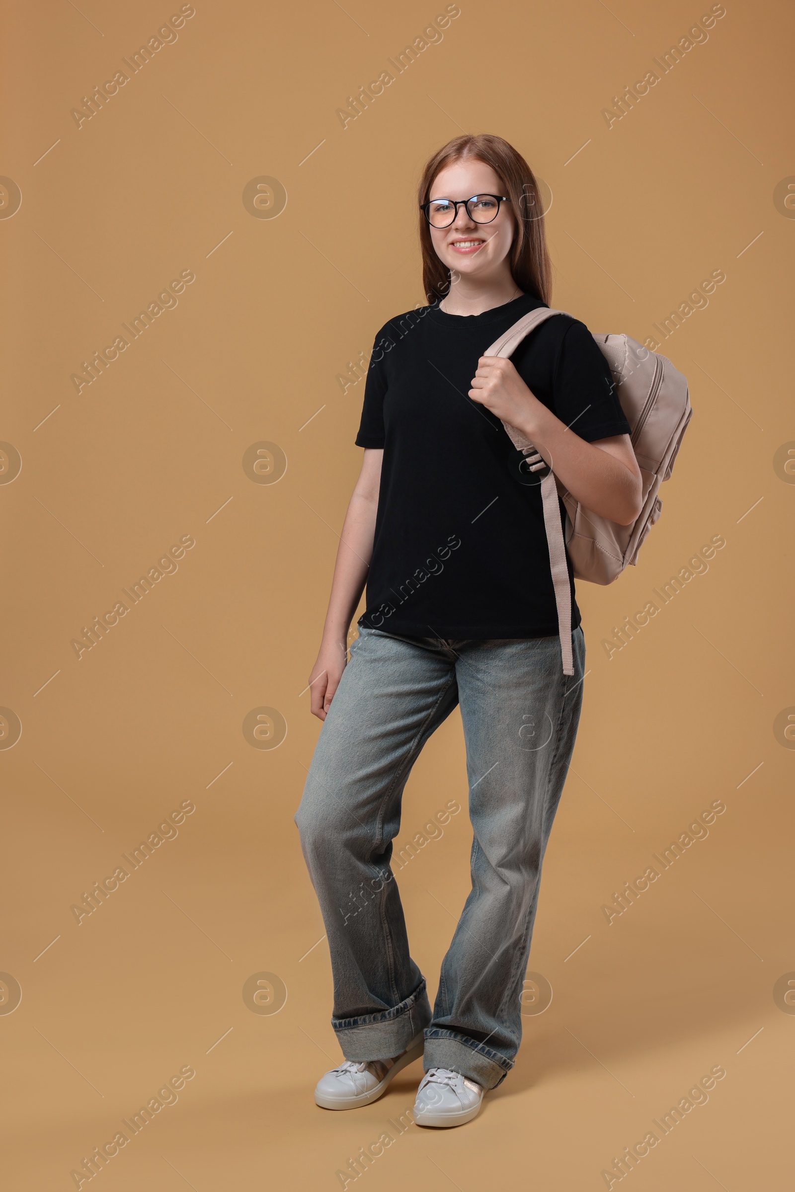 Photo of Teenage girl with backpack on beige background