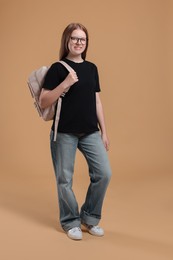 Photo of Teenage girl with backpack on beige background