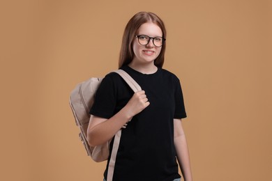 Teenage girl with backpack on beige background