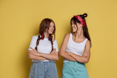 Photo of Happy teenage girls with crossed arms on yellow background