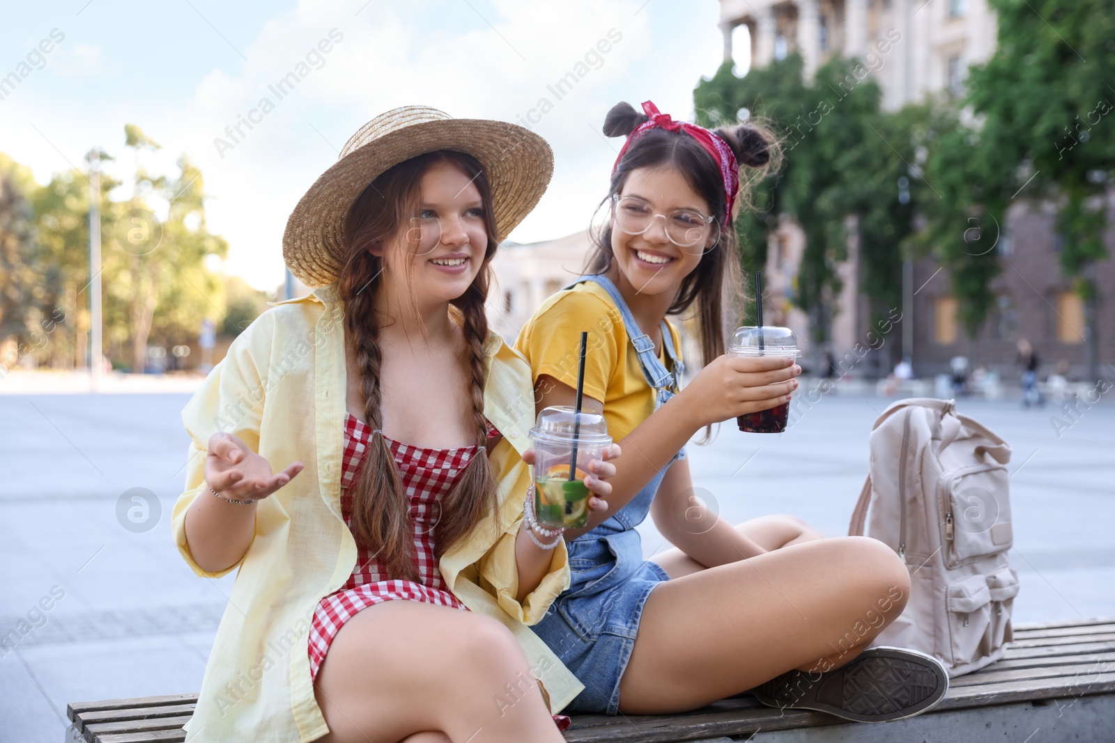 Photo of Happy teenage friends sitting on bench outdoors