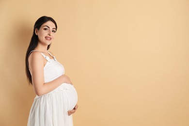 Photo of Portrait of beautiful pregnant woman on beige background, space for text