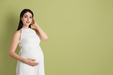 Portrait of beautiful pregnant woman on light olive background, space for text