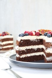 Photo of Delicious chocolate sponge cake with berries on white wooden table, closeup