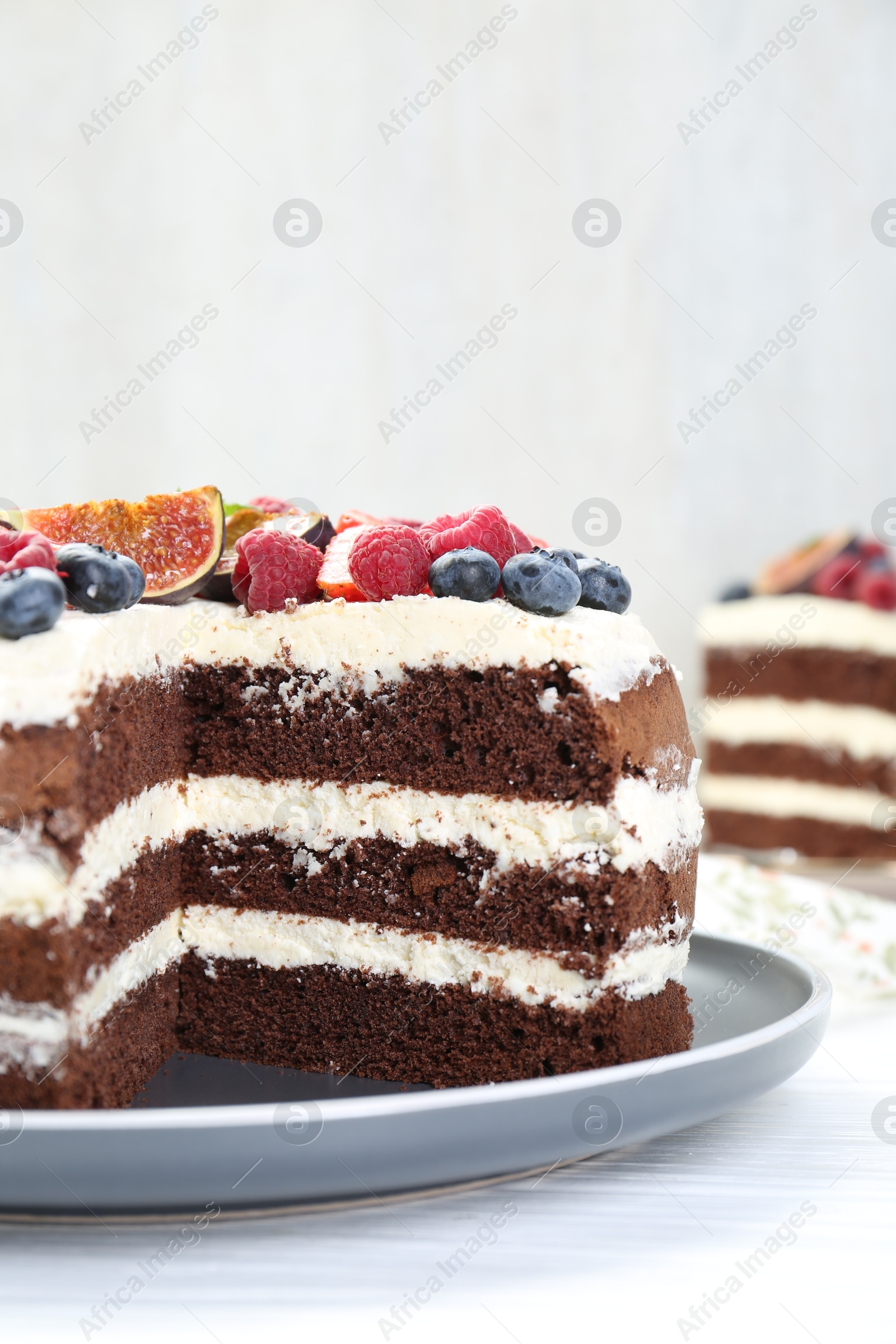 Photo of Delicious chocolate sponge cake with berries on white wooden table, closeup