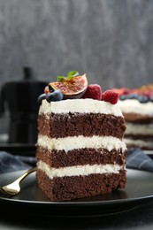 Piece of delicious chocolate sponge cake with berries on table, closeup