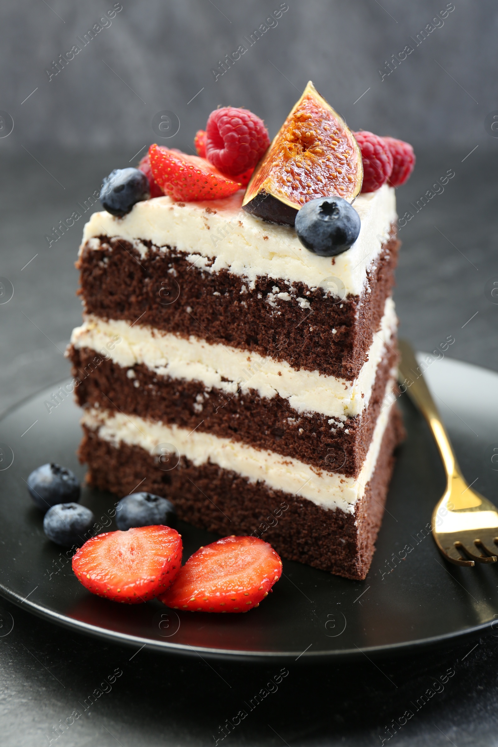 Photo of Piece of delicious chocolate sponge cake with berries on table, closeup