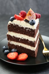 Piece of delicious chocolate sponge cake with berries on table, closeup