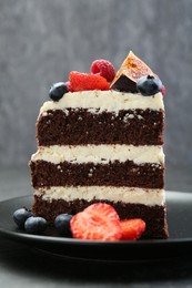 Piece of delicious chocolate sponge cake with berries on table, closeup