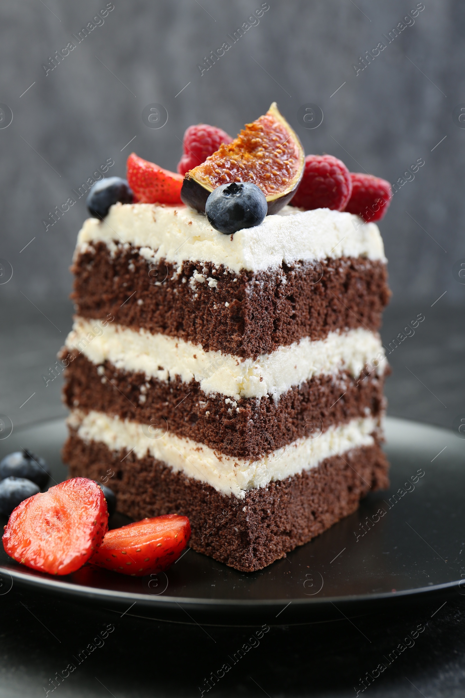 Photo of Piece of delicious chocolate sponge cake with berries on table, closeup