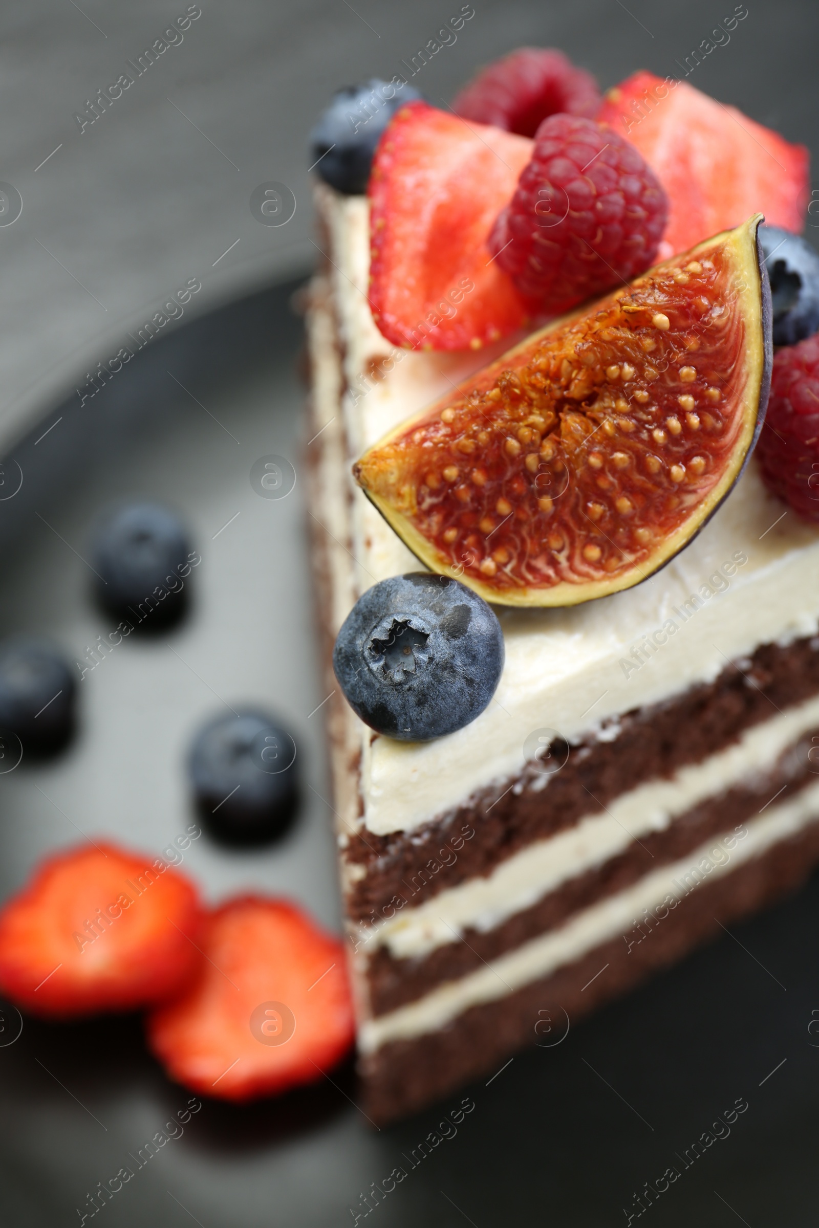 Photo of Piece of delicious chocolate sponge cake with berries on table, closeup