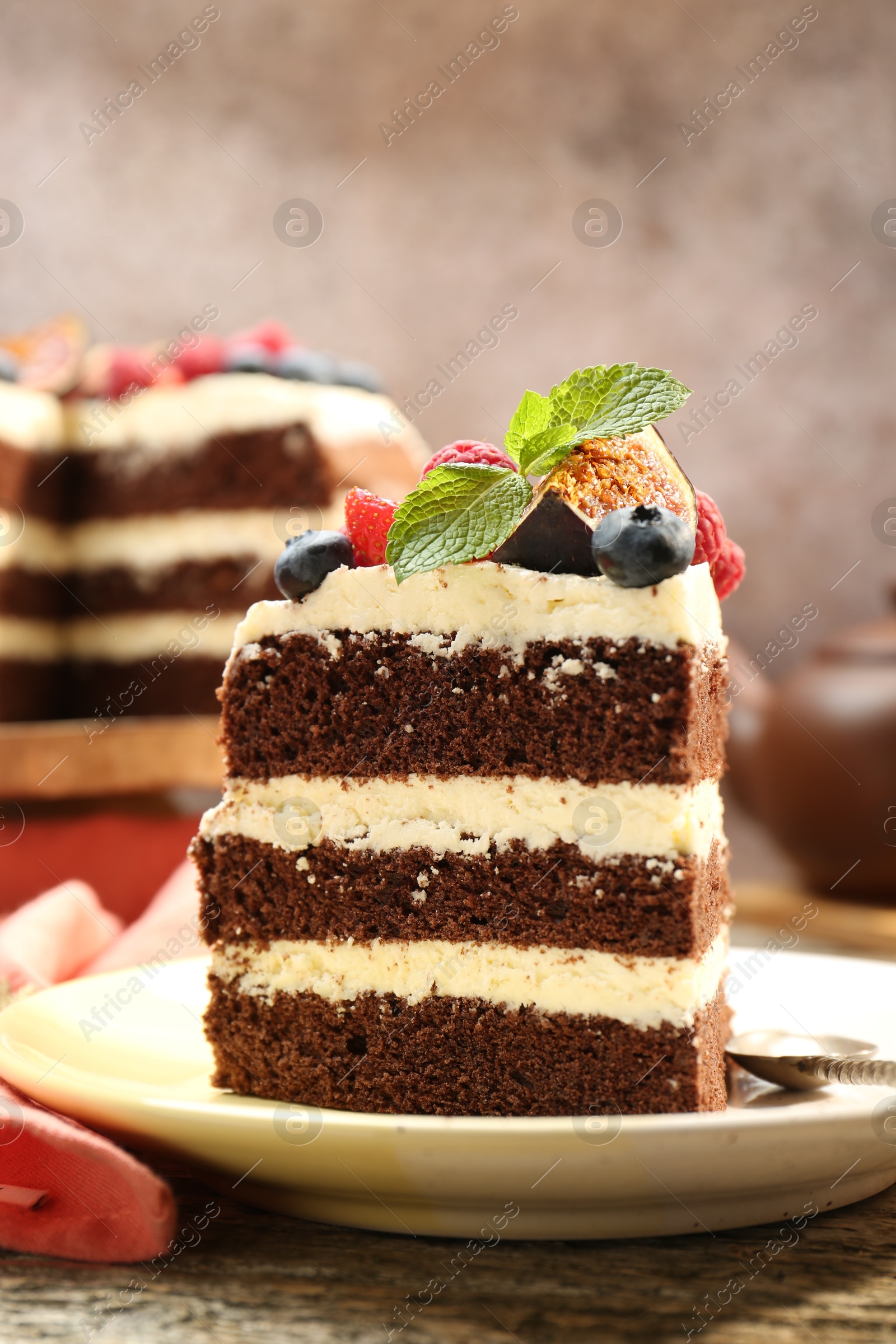 Photo of Piece of delicious chocolate sponge cake with berries on wooden table, closeup