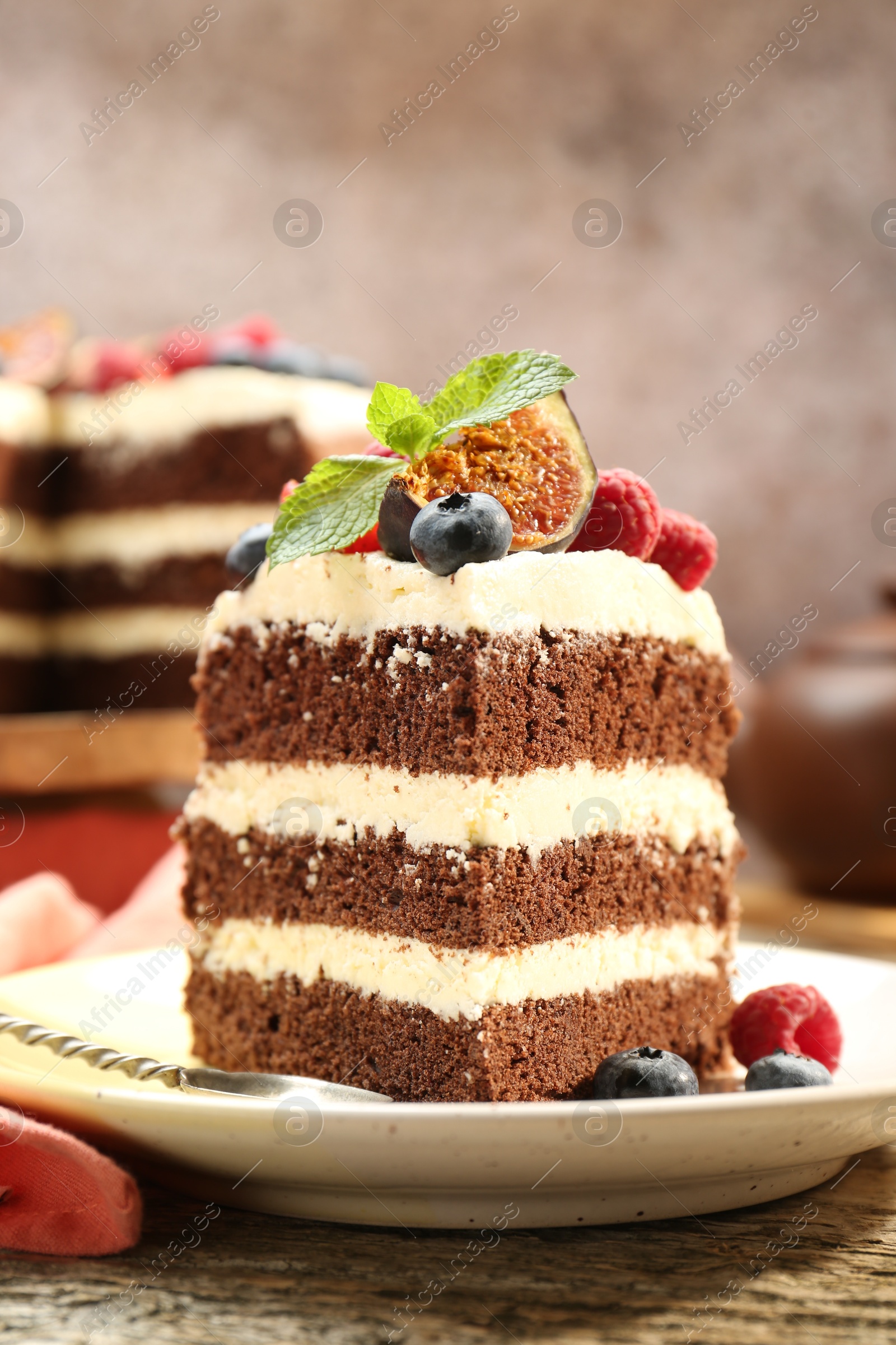 Photo of Piece of delicious chocolate sponge cake with berries on wooden table, closeup