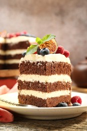 Photo of Piece of delicious chocolate sponge cake with berries on wooden table, closeup