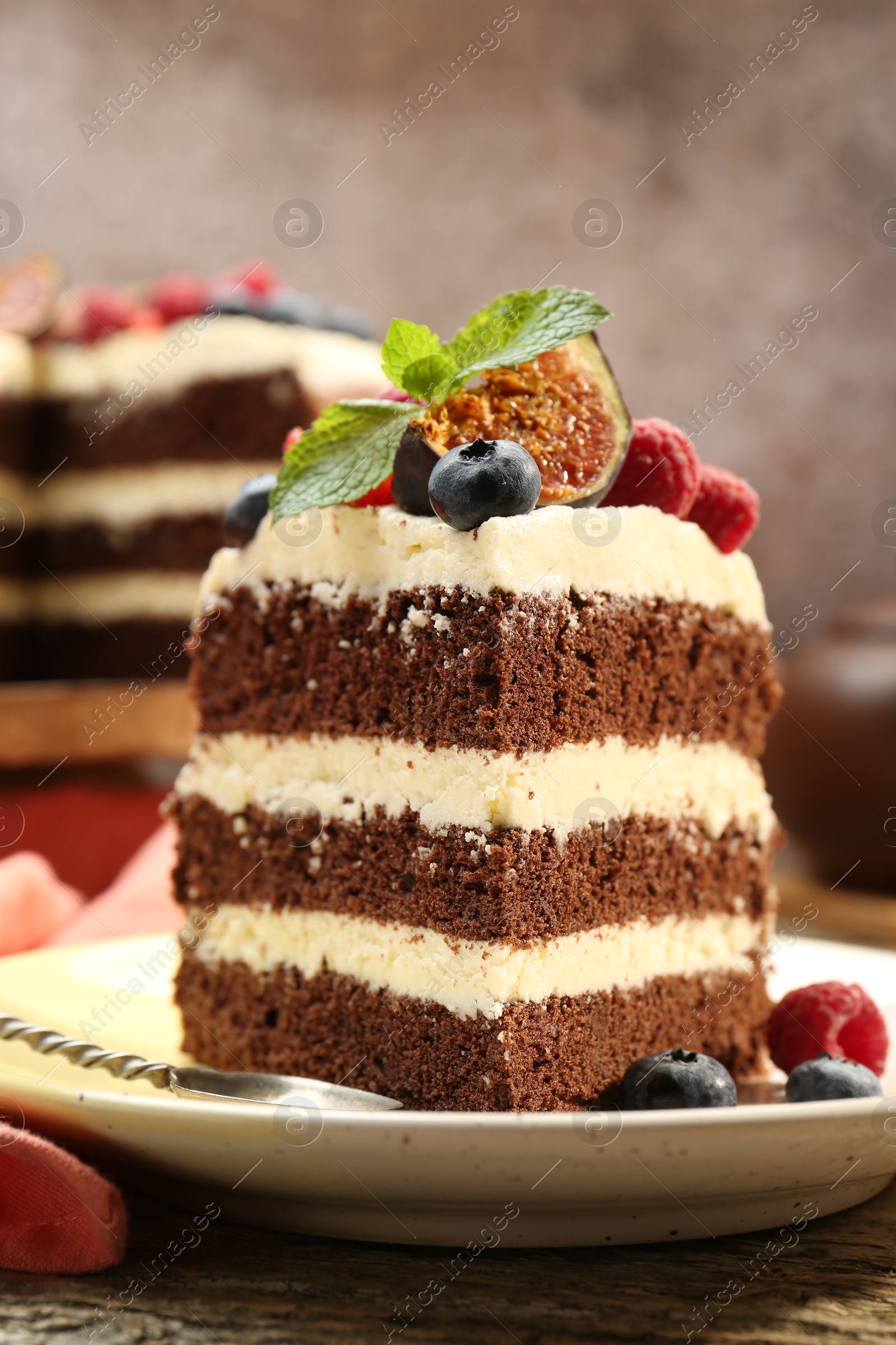 Photo of Piece of delicious chocolate sponge cake with berries on wooden table, closeup