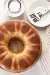 Freshly baked sponge cake served on white wooden table, top view