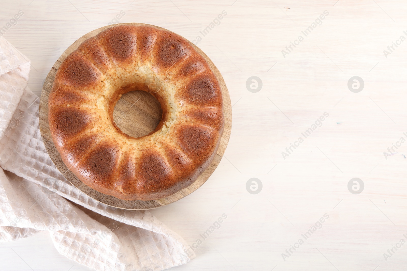 Photo of Freshly baked sponge cake on white wooden table, top view. Space for text