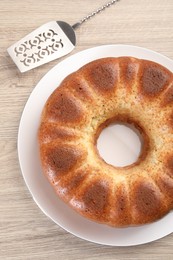 Photo of Freshly baked sponge cake and server on wooden table, top view