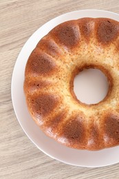 Freshly baked sponge cake on wooden table, top view