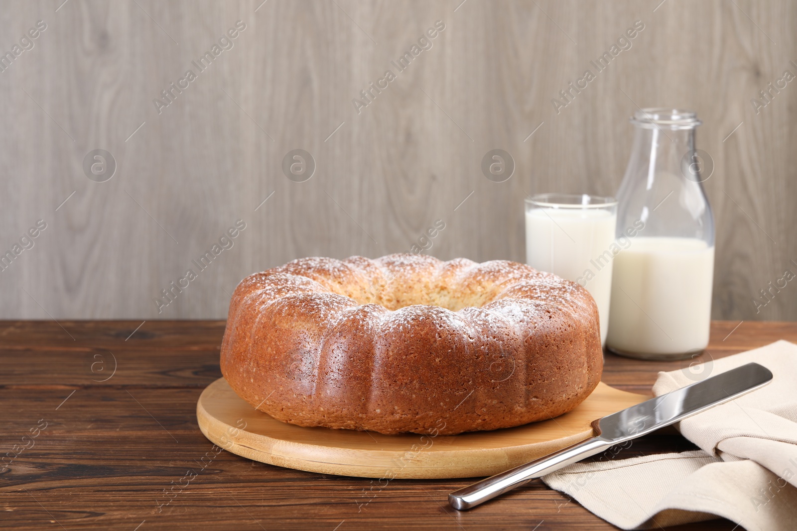 Photo of Freshly baked sponge cake, knife and milk on wooden table