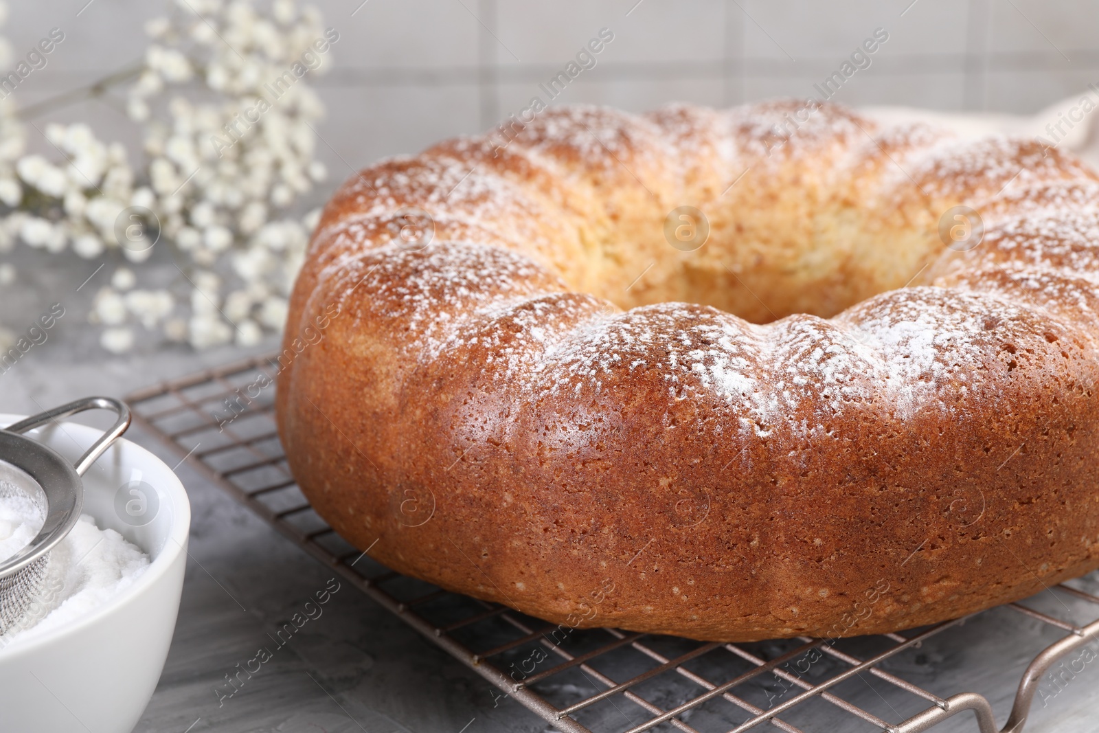 Photo of Freshly baked sponge cake with powdered sugar on grey table, closeup