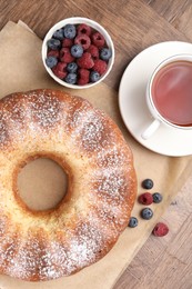 Freshly baked sponge cake, tea and berries on wooden table, top view