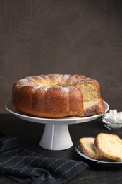 Freshly baked sponge cake, sugar cubes and coffee on black table