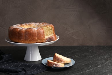 Freshly baked sponge cake on black table, space for text