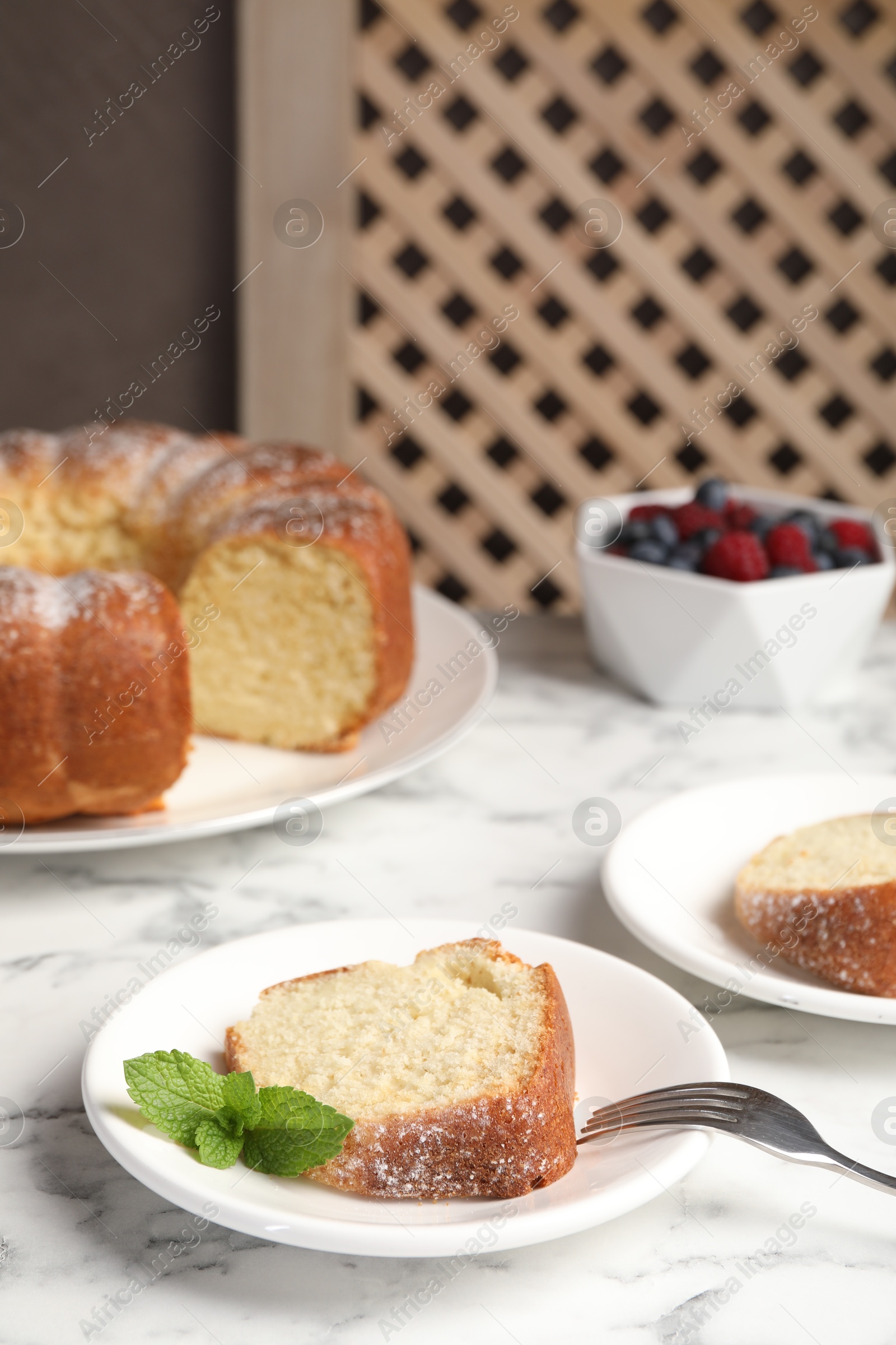 Photo of Freshly baked sponge cake, mint and berries on white marble table