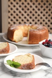 Photo of Freshly baked sponge cake, mint and berries on white marble table