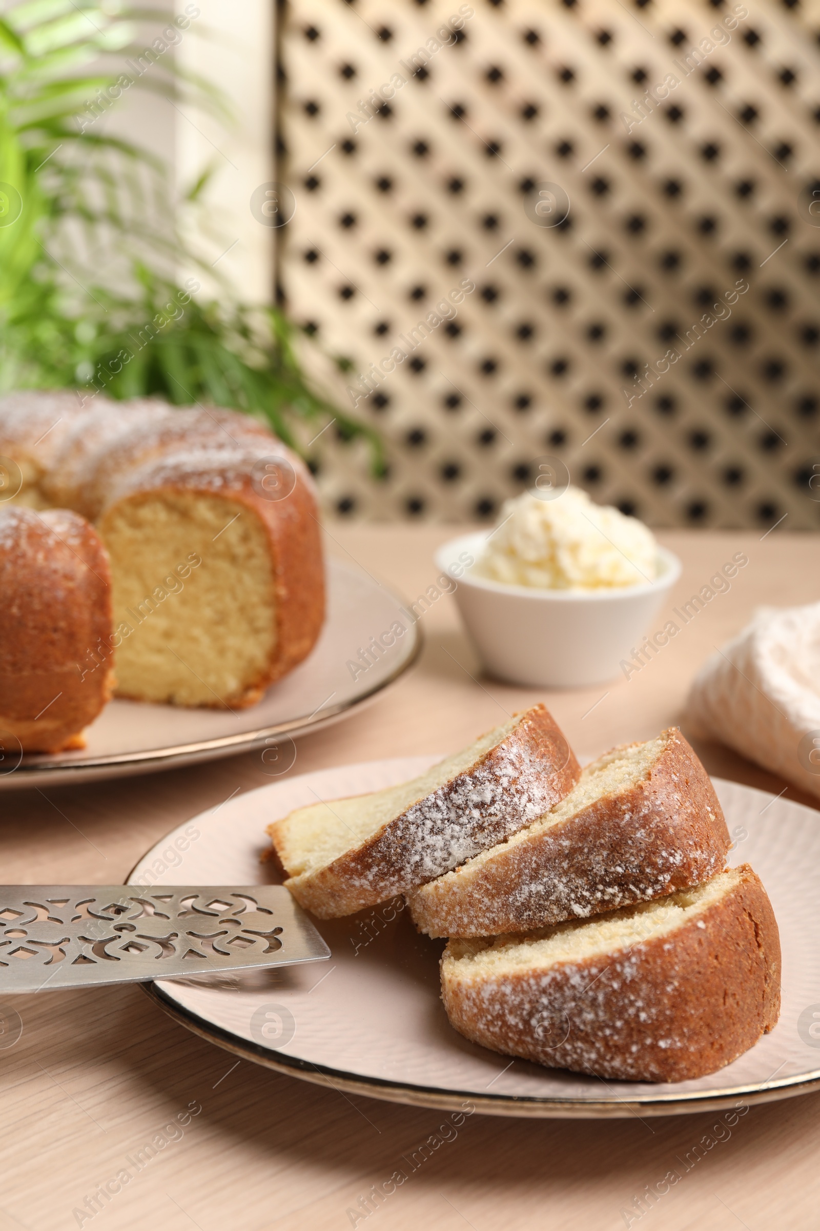 Photo of Pieces of freshly baked sponge cake, server and ice cream on wooden table, closeup