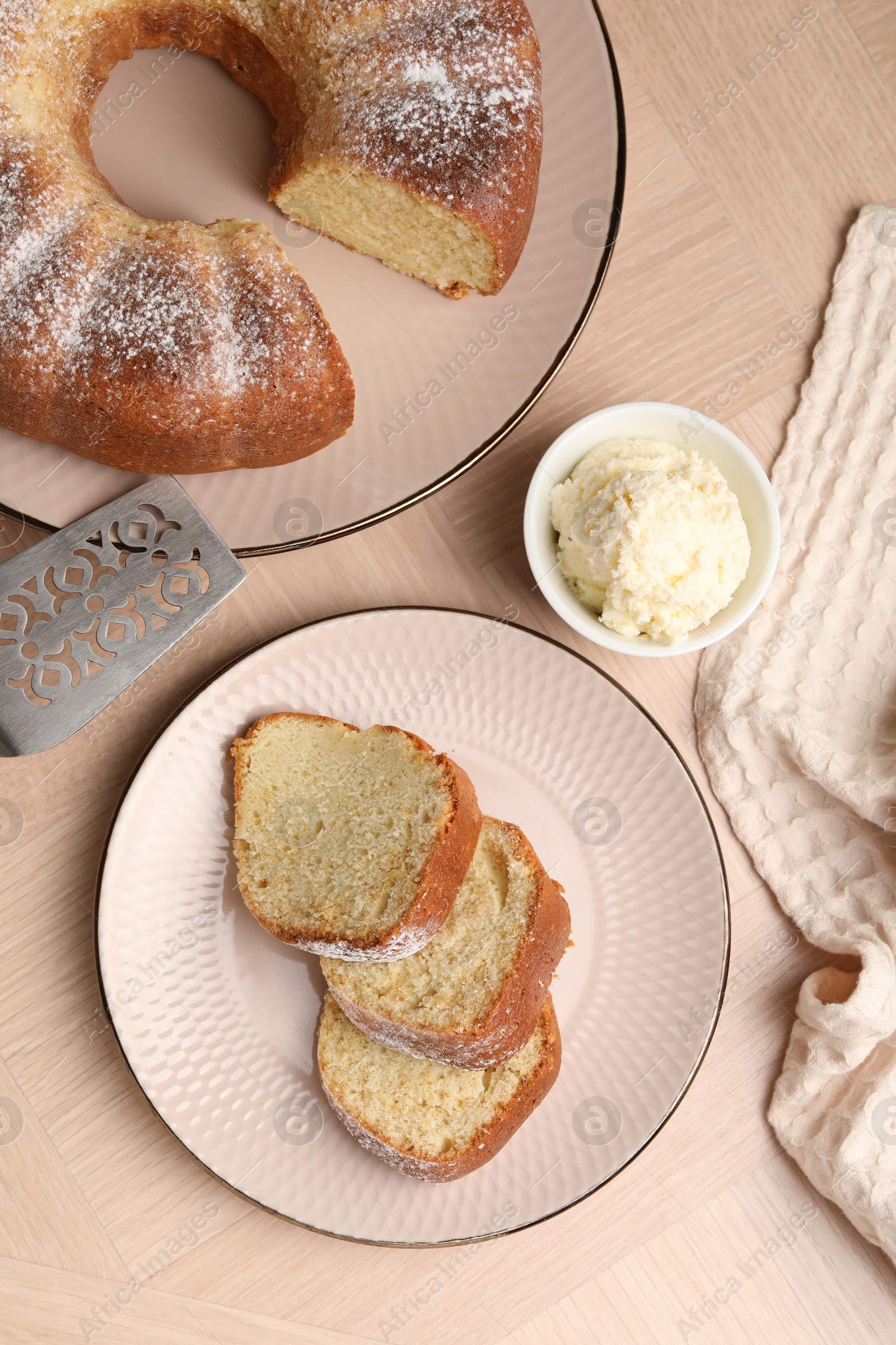 Photo of Pieces of freshly baked sponge cake, server and ice cream on wooden table, top view