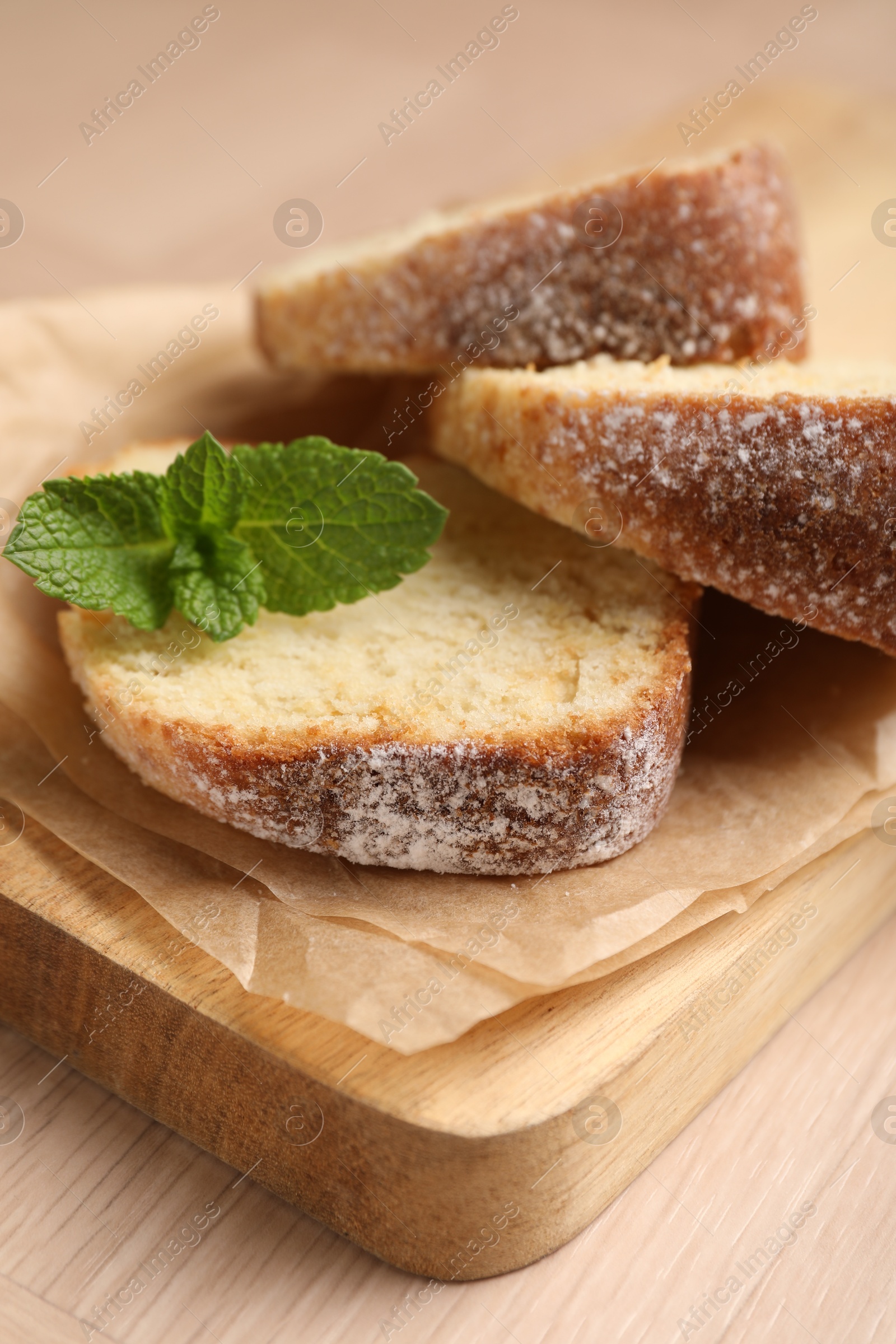 Photo of Pieces of freshly baked sponge cake and mint on wooden table, closeup