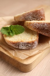 Pieces of freshly baked sponge cake and mint on wooden table, closeup