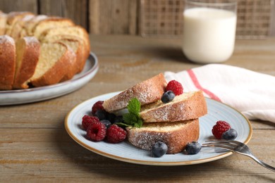 Photo of Pieces of freshly baked sponge cake, berries and milk on wooden table, closeup