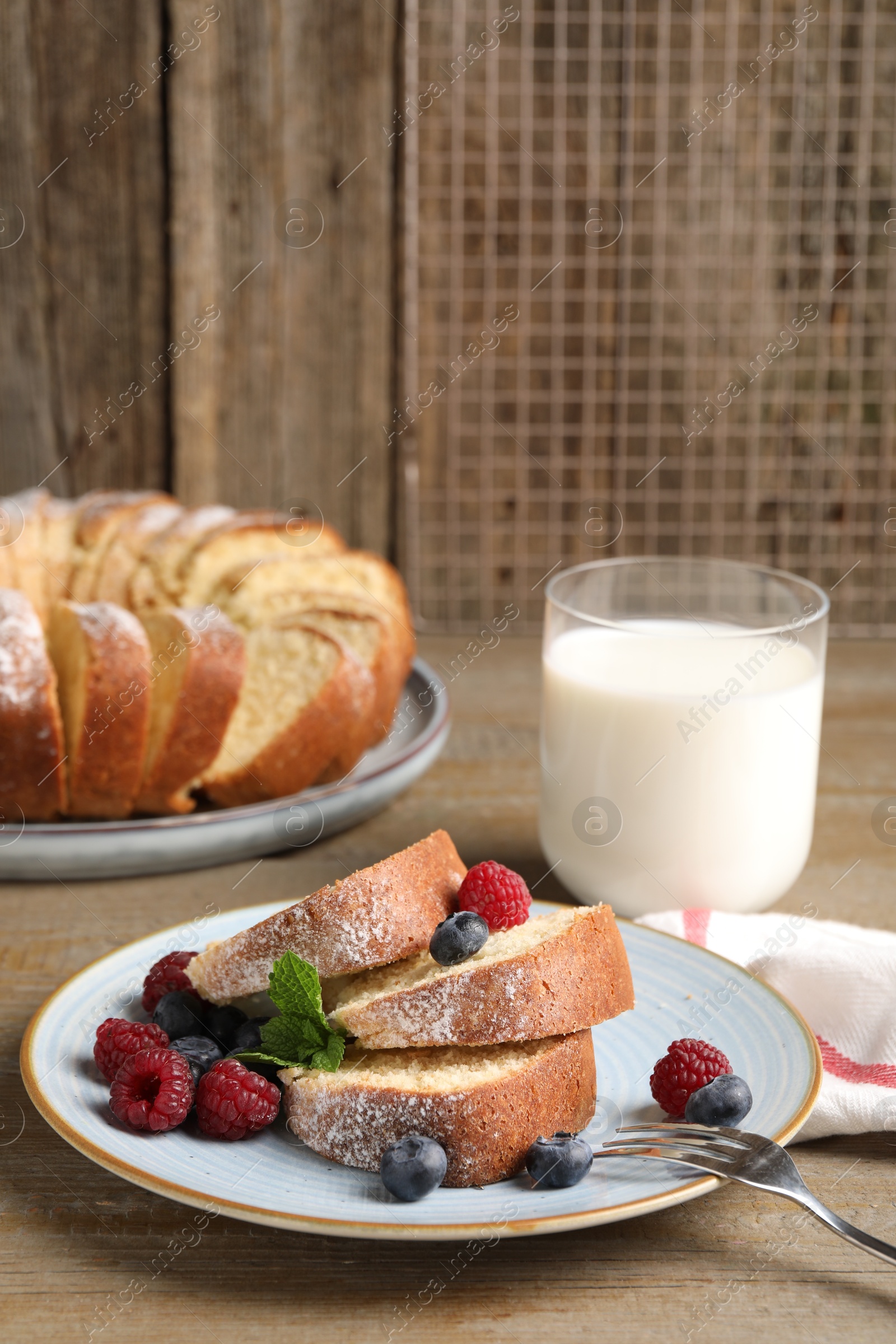 Photo of Pieces of freshly baked sponge cake, berries and milk on wooden table