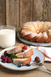 Photo of Pieces of freshly baked sponge cake, berries and milk on wooden table