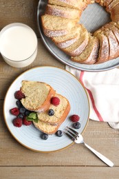 Pieces of freshly baked sponge cake, berries and milk on wooden table, flat lay