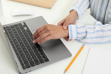 Photo of Carpal tunnel syndrome. Woman suffering from pain in wrist at desk, closeup