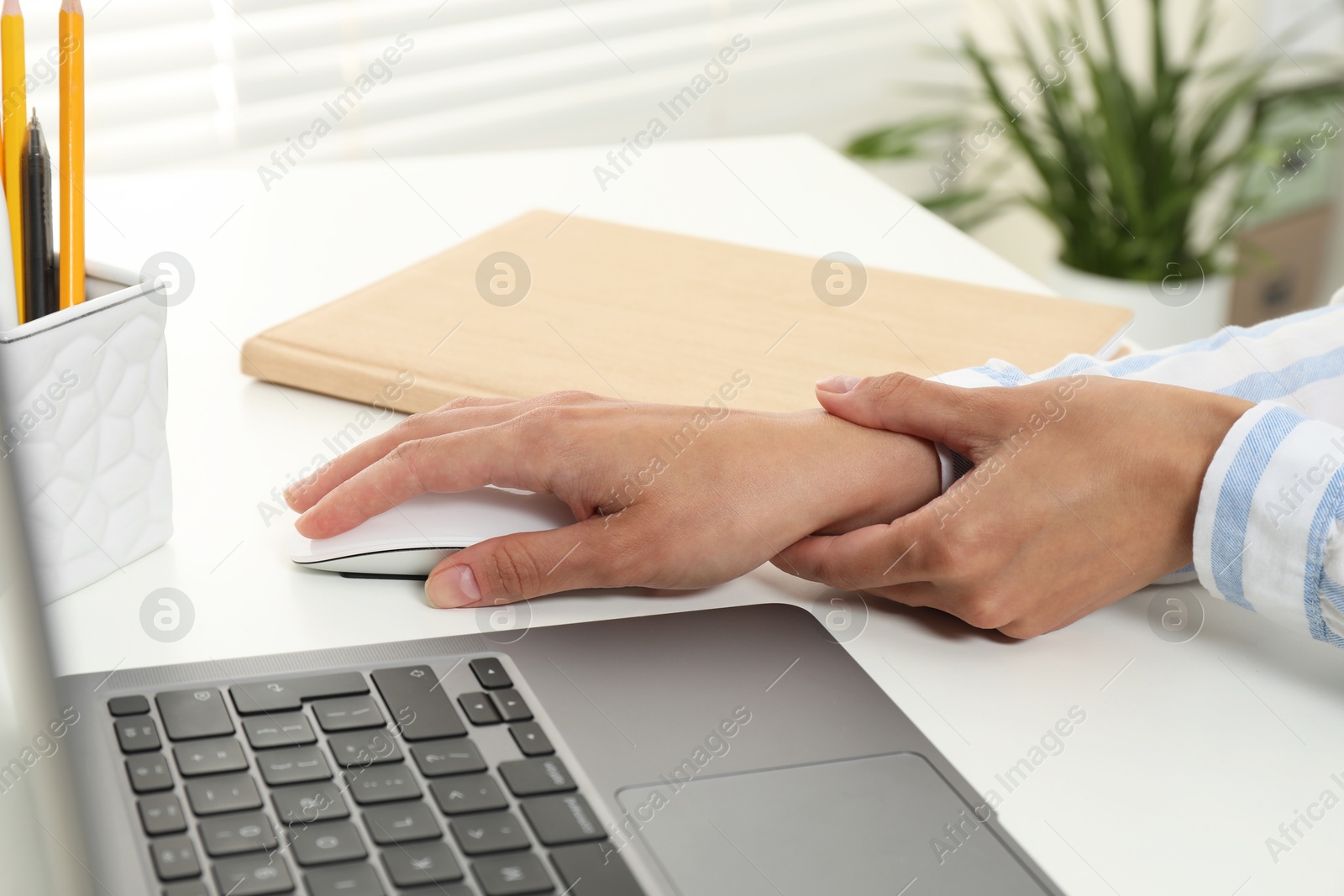 Photo of Carpal tunnel syndrome. Woman suffering from pain in wrist at desk indoors, closeup