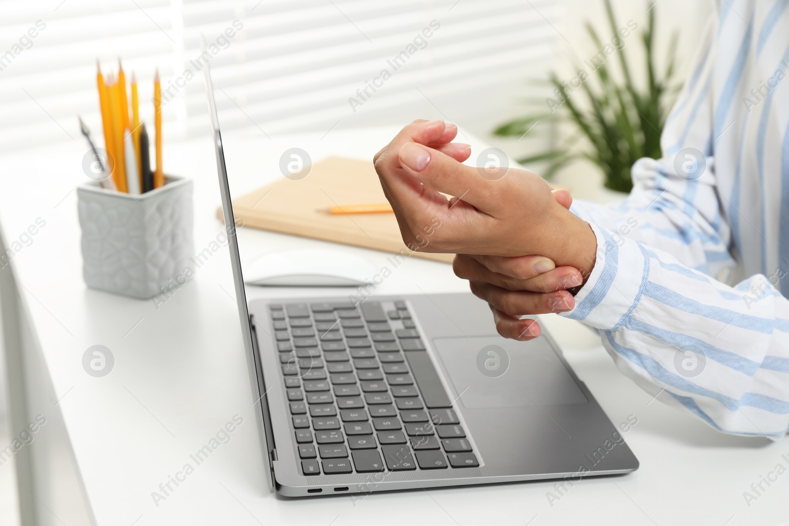 Photo of Carpal tunnel syndrome. Woman suffering from pain in wrist at desk indoors, closeup