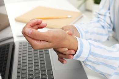 Photo of Carpal tunnel syndrome. Woman suffering from pain in wrist at desk, closeup