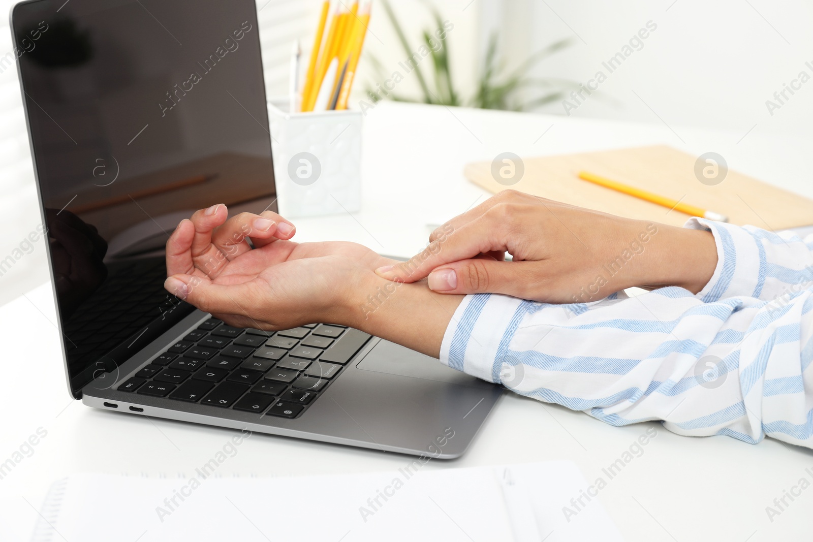 Photo of Carpal tunnel syndrome. Woman suffering from pain in wrist at desk indoors, closeup