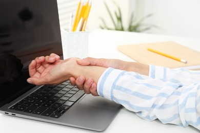 Photo of Carpal tunnel syndrome. Woman suffering from pain in wrist at desk indoors, closeup