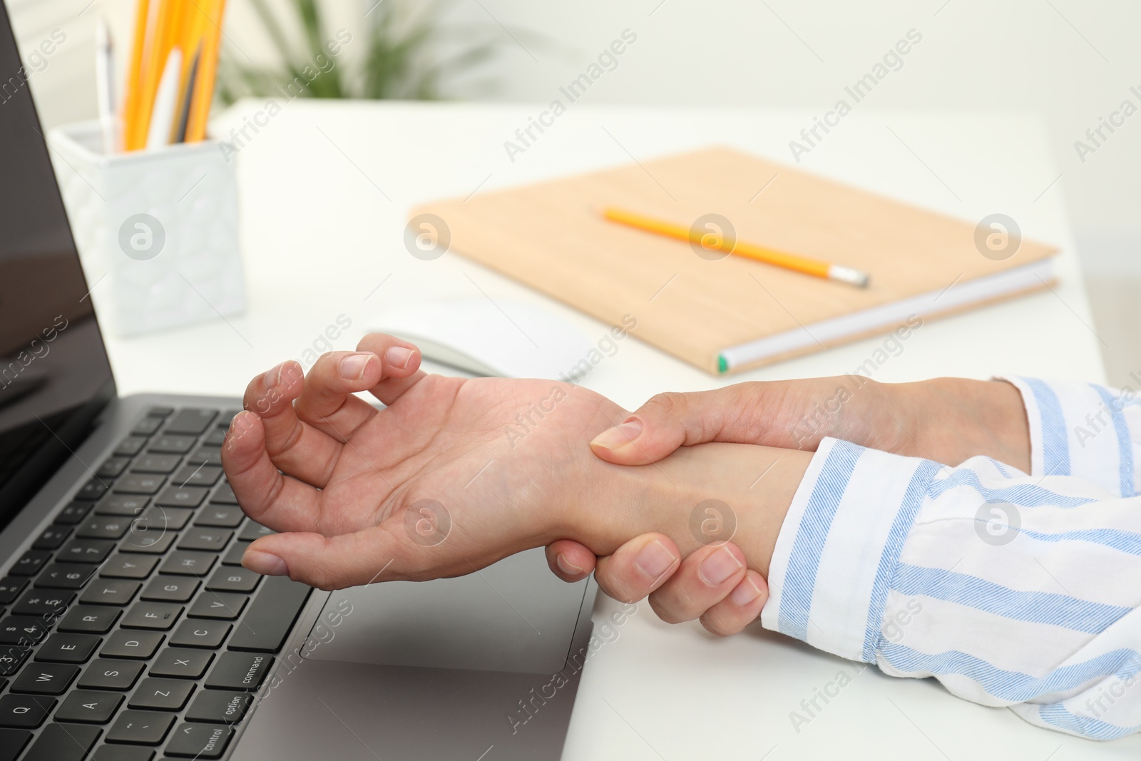 Photo of Carpal tunnel syndrome. Woman suffering from pain in wrist at desk indoors, closeup