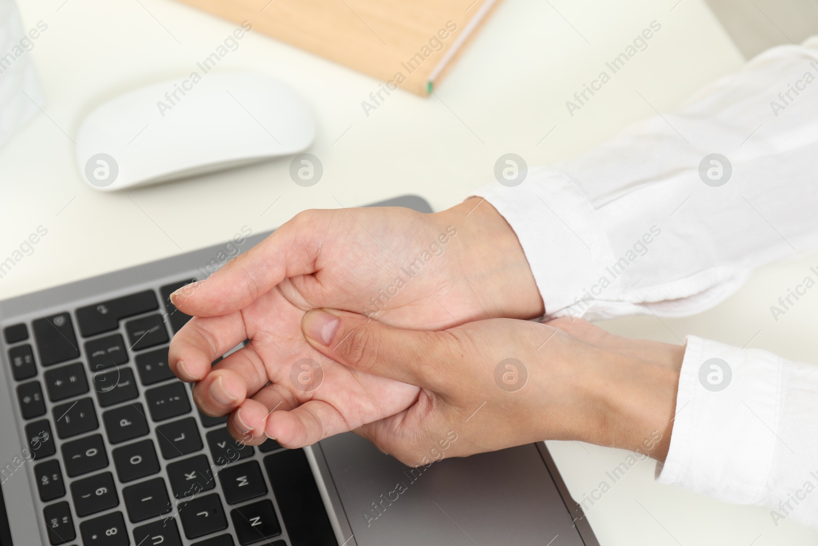 Photo of Carpal tunnel syndrome. Woman suffering from pain in wrist at desk, closeup