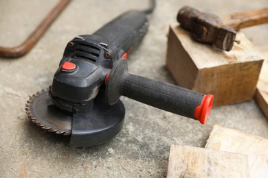 Angle grinder, hammer and wooden planks on asphalt outdoors, closeup