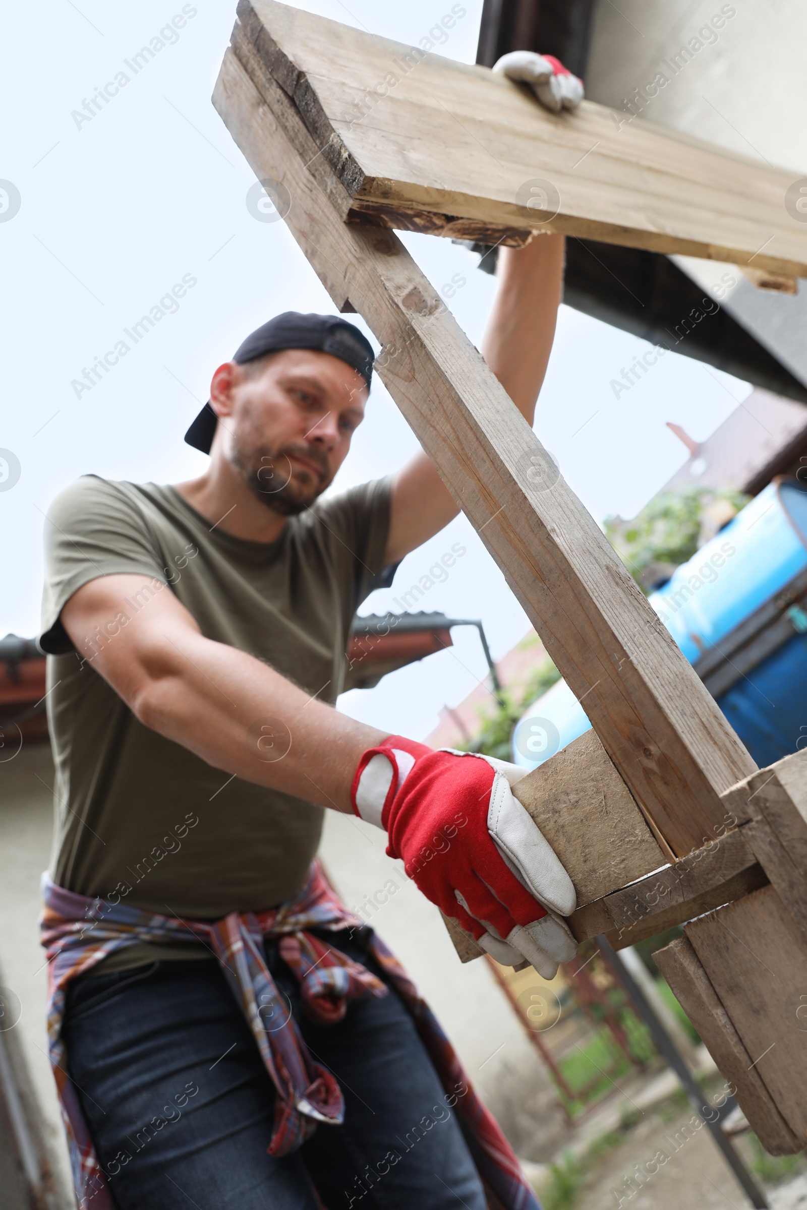 Photo of Man working with wooden planks outdoors, low angle view